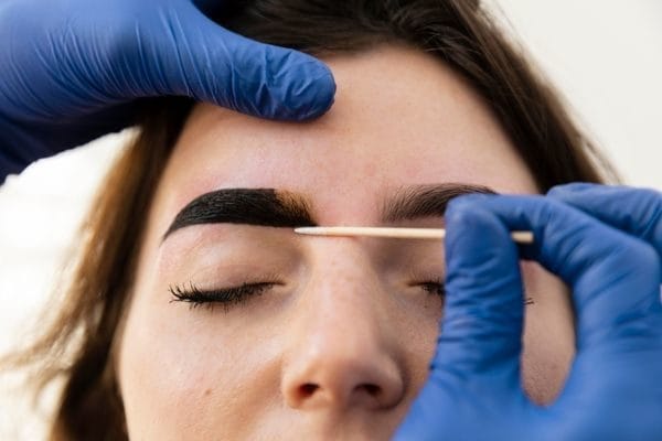 beautician applies henna to eyebrows