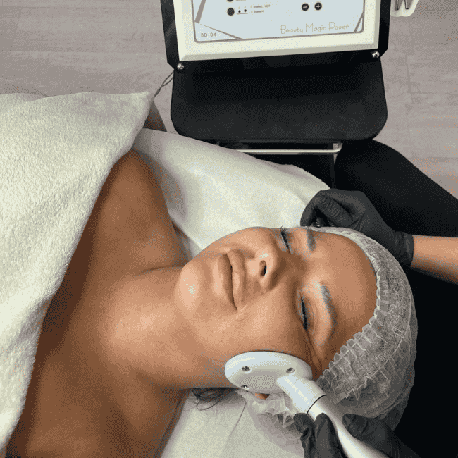 kosmetyczka wykonuje zabieg nożyczki liftingujące. Głowica urządzenia prowadzona po twarzy klientki.