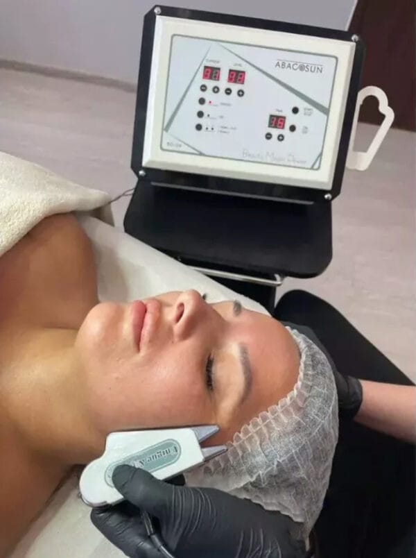 The beautician applies the heads to Joanna's face