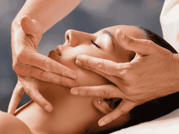 masaż twarzy w trakcie - kosmetyczka masuje kość żuchwy