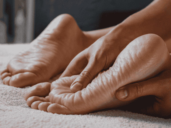 refleksolog wykonuje zabieg na stopach uciskając punkty