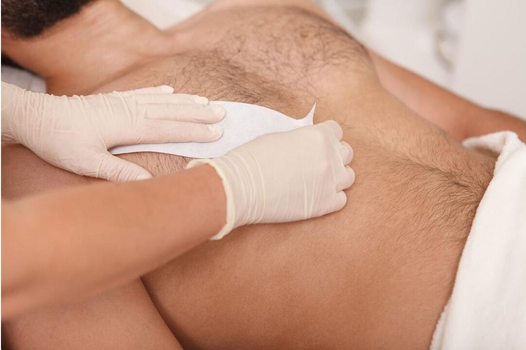 kosmetyczka używa wosku do depilacji klatki piersiowej klienta